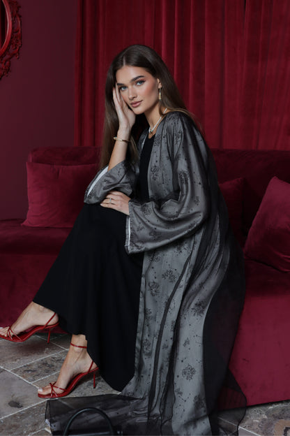Woman in a gray dress with a black clutch sitting on a red couch.